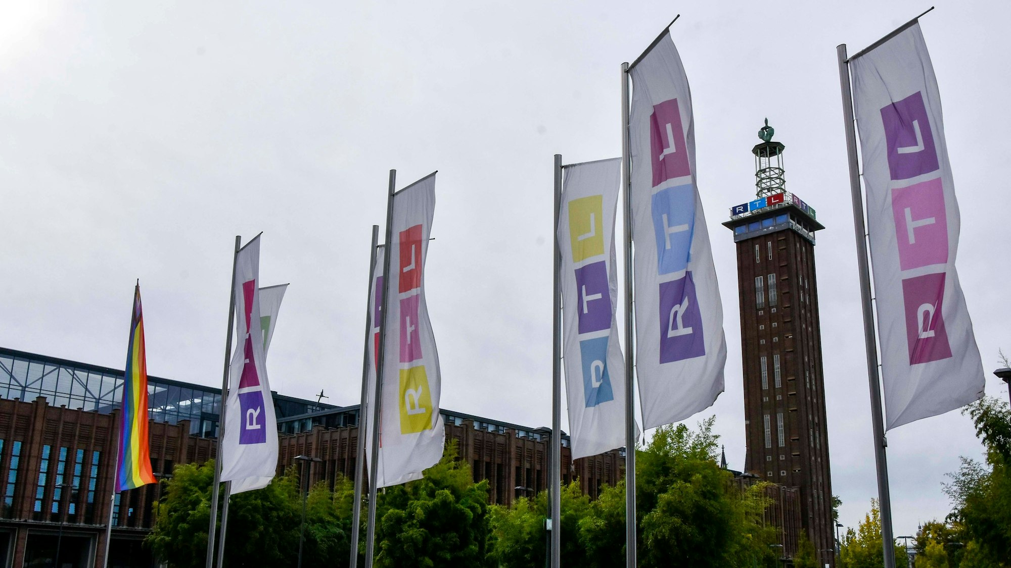 Der Kölner Messe Turm, davor bunte Fahnen mit dem RTL Logo in Deutz am Picassoplatz