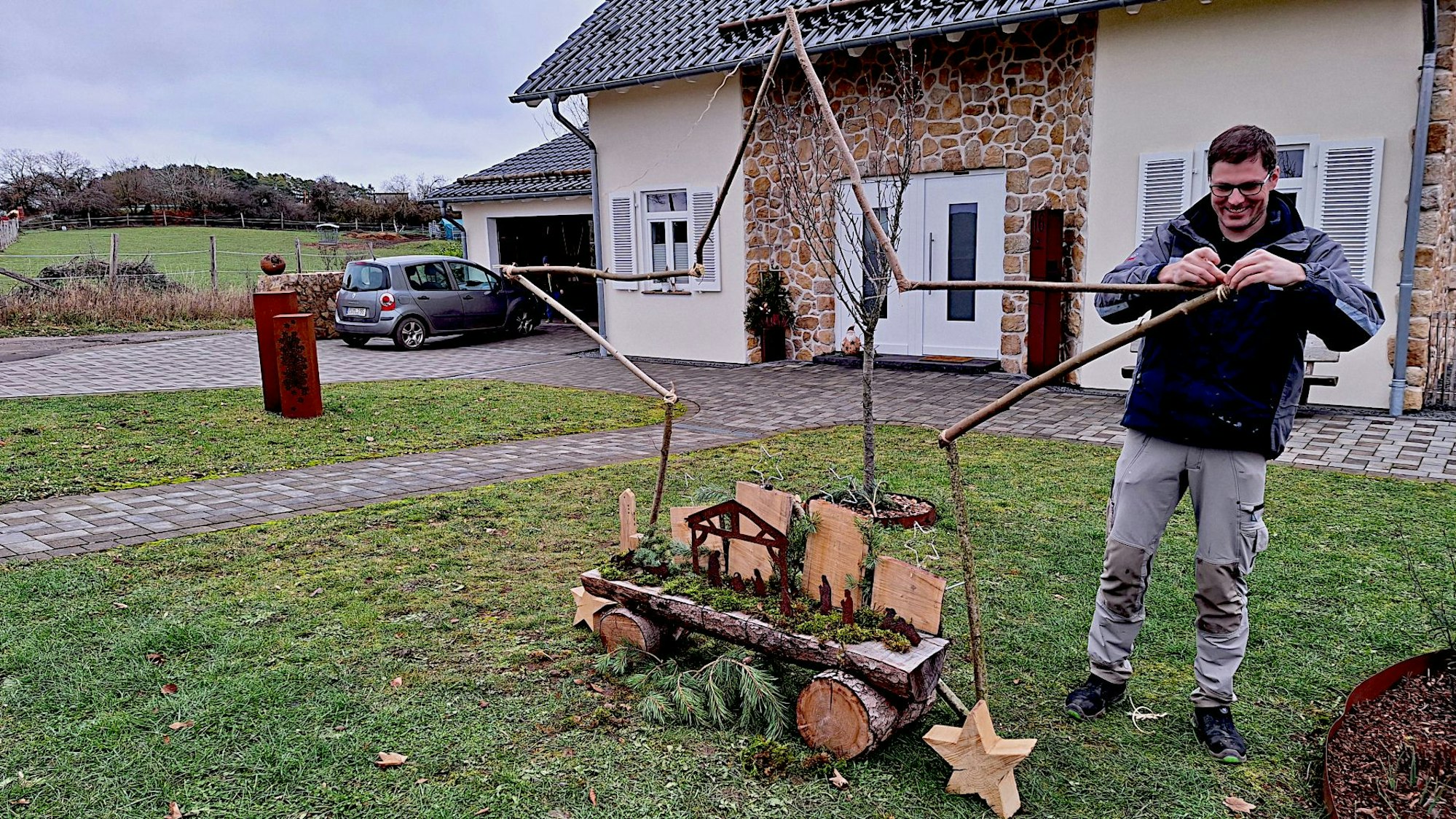 Patrick Plötzer steht vor seinem Wohnhaus. Aus Ästen bindet er einen Stern für seine Krippe, die zum Krippenweg in Blankenheim-Ripsdorf gehört.