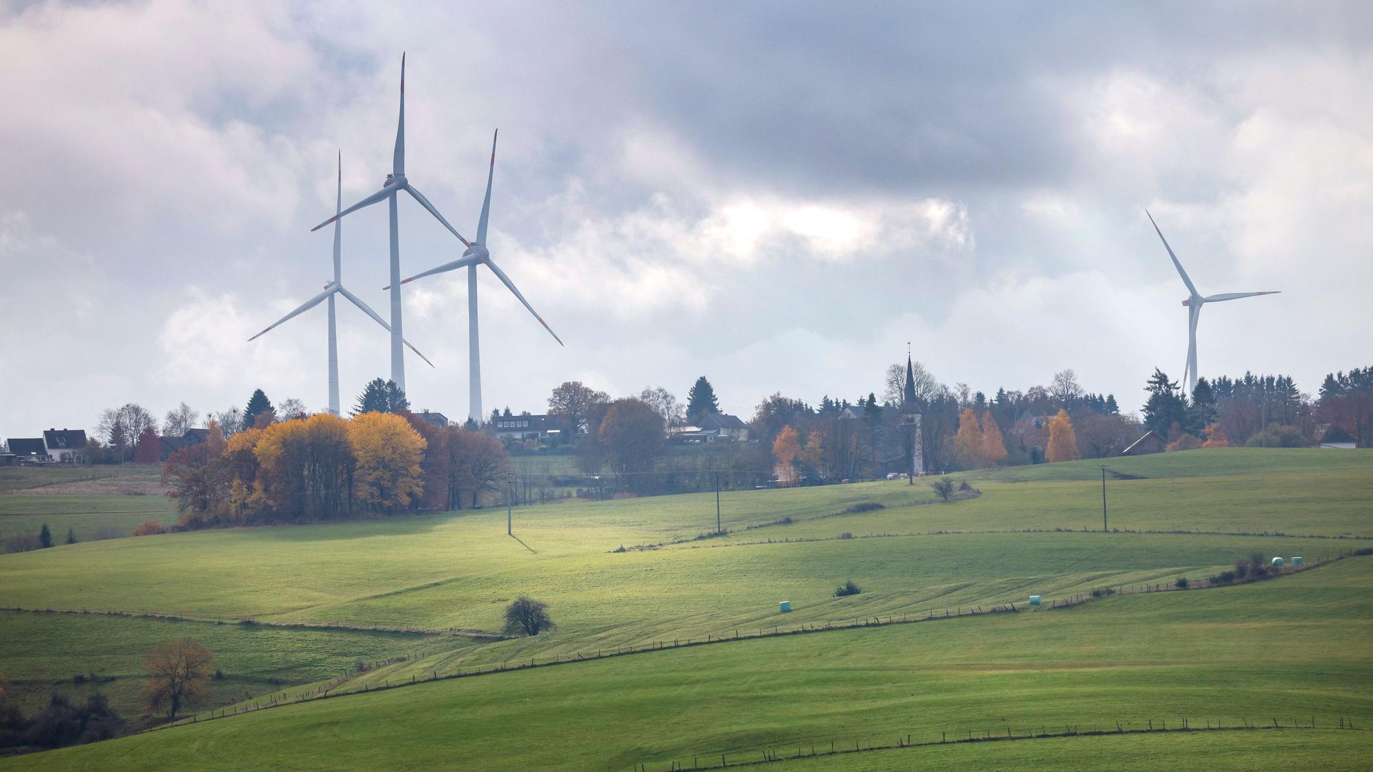 Windräder ragen über die herbstlich gefärbte Landschaft empor.