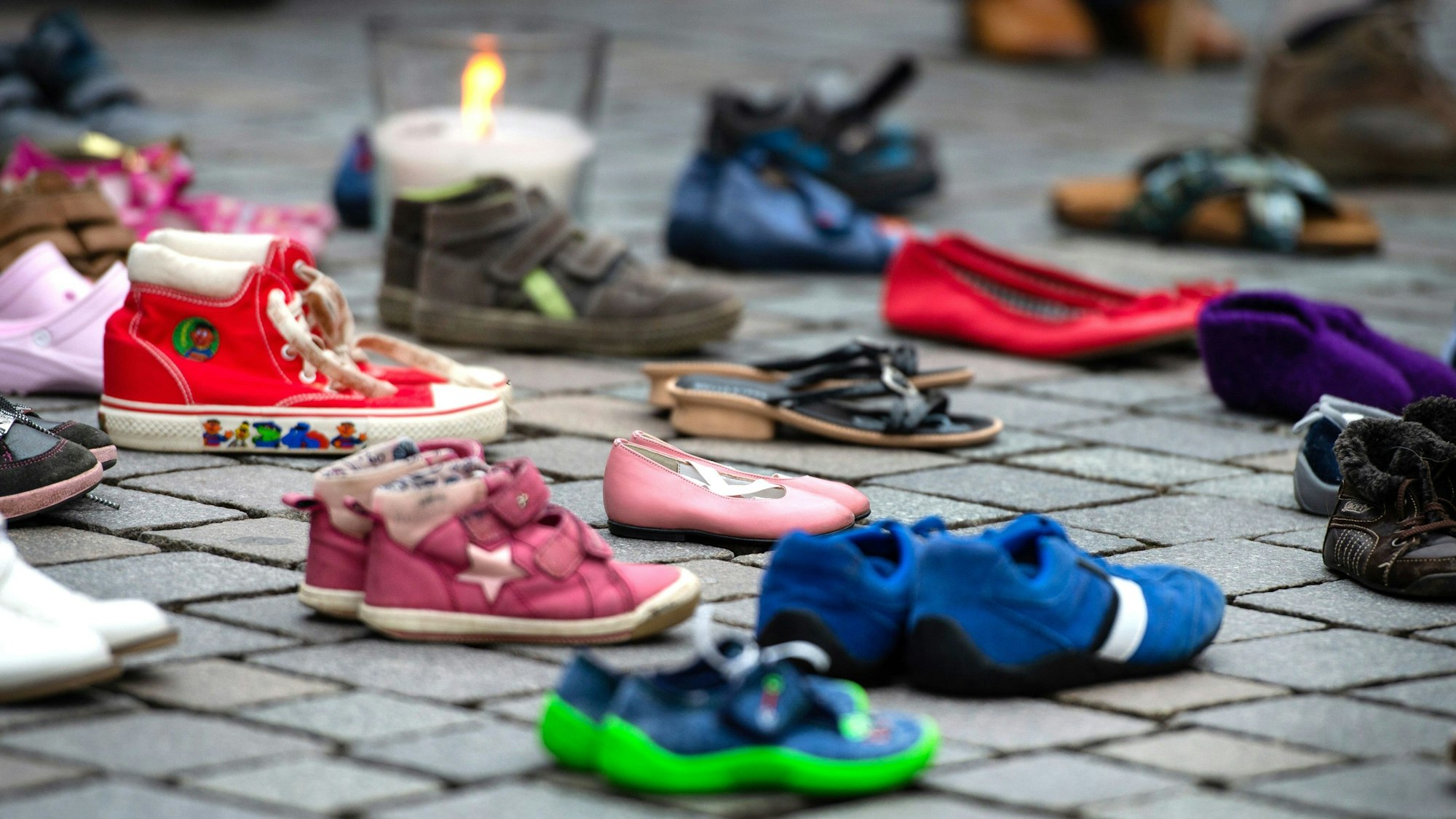 Auf Pflastersteinen stehen Kinderschuhe.