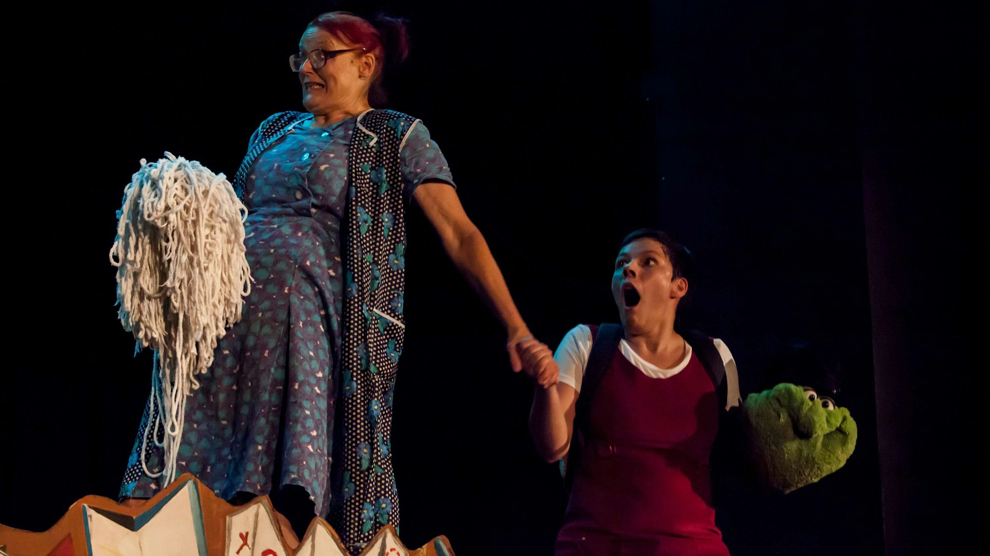 Zwei Schauspielerinnen agieren auf einer Bühne.