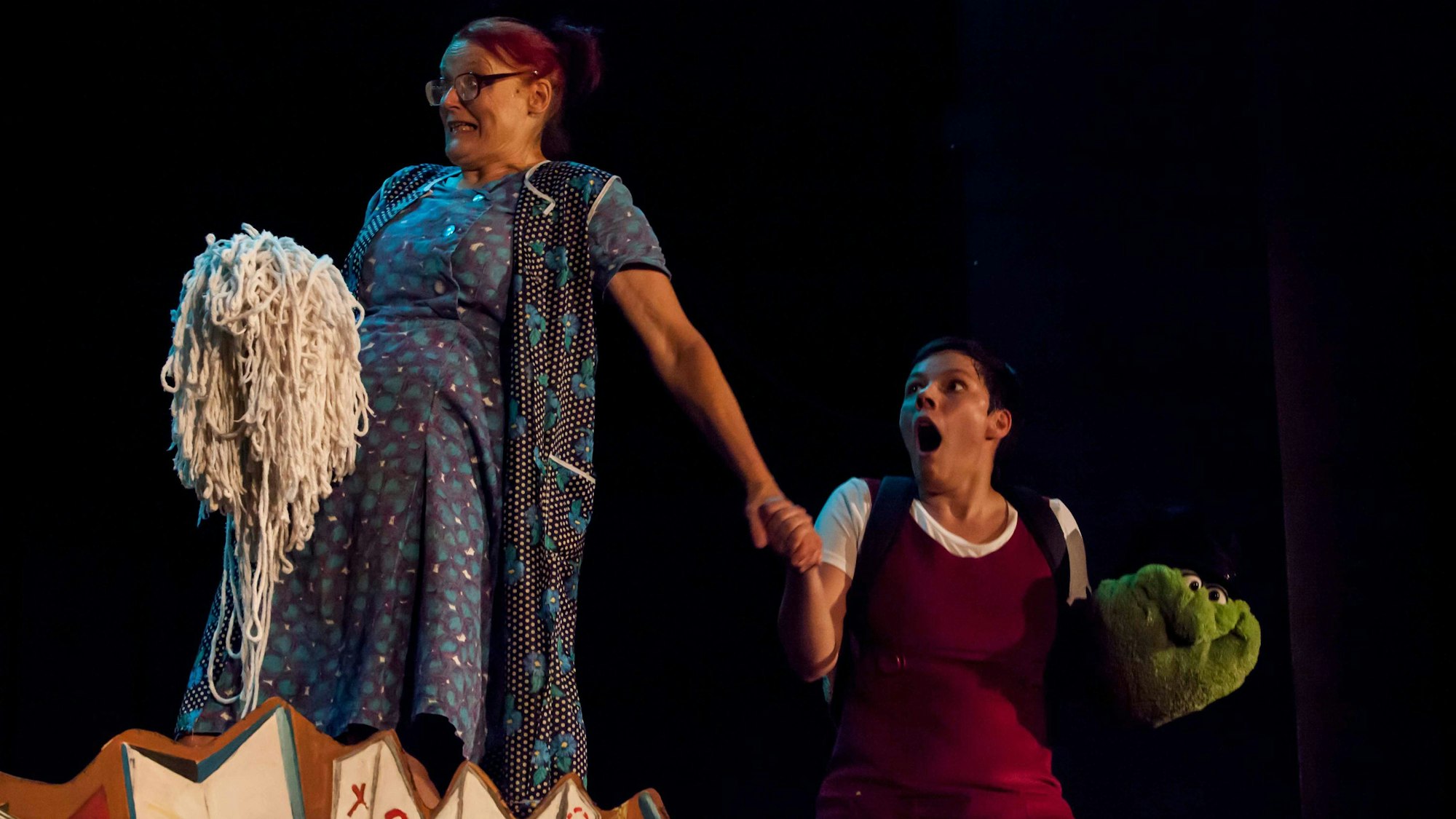 Zwei Schauspielerinnen agieren auf einer Bühne.