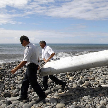 Techniker tragen ein Wrackteil, die Flügelklappe eines Flugzeugs, über einen Strand bei Saint-Andre de la Reunion. Die Suche nach dem Wrack des vor elfeinhalb Jahren verschollenen Fluges MH370 der Malaysia Airlines wird noch in diesem Jahr fortgesetzt.