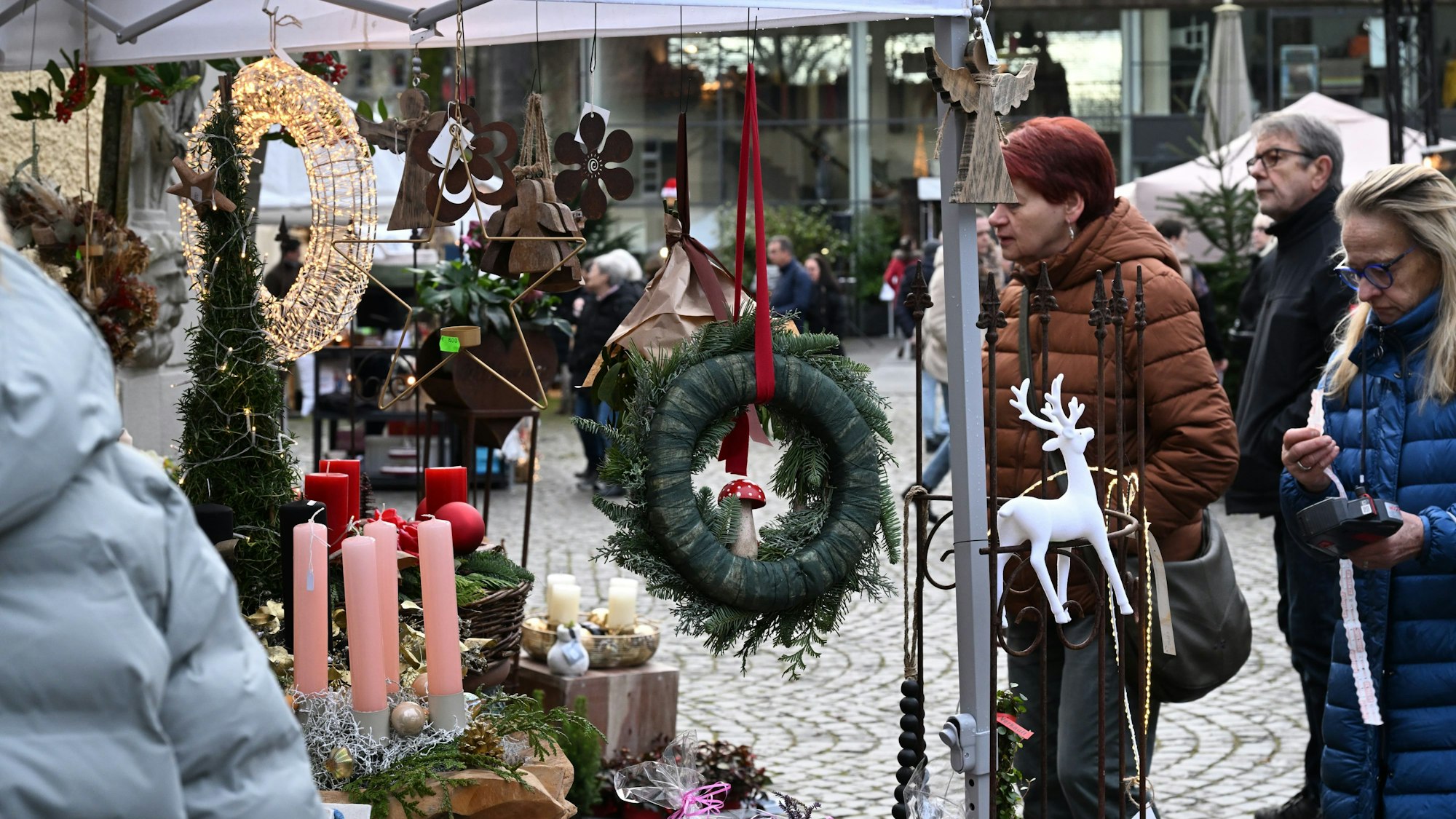 Besucherinnen und Besucher des Weihnachtsmarktes auf Schloss Eulenbroich betrachten Deko-Artikel.