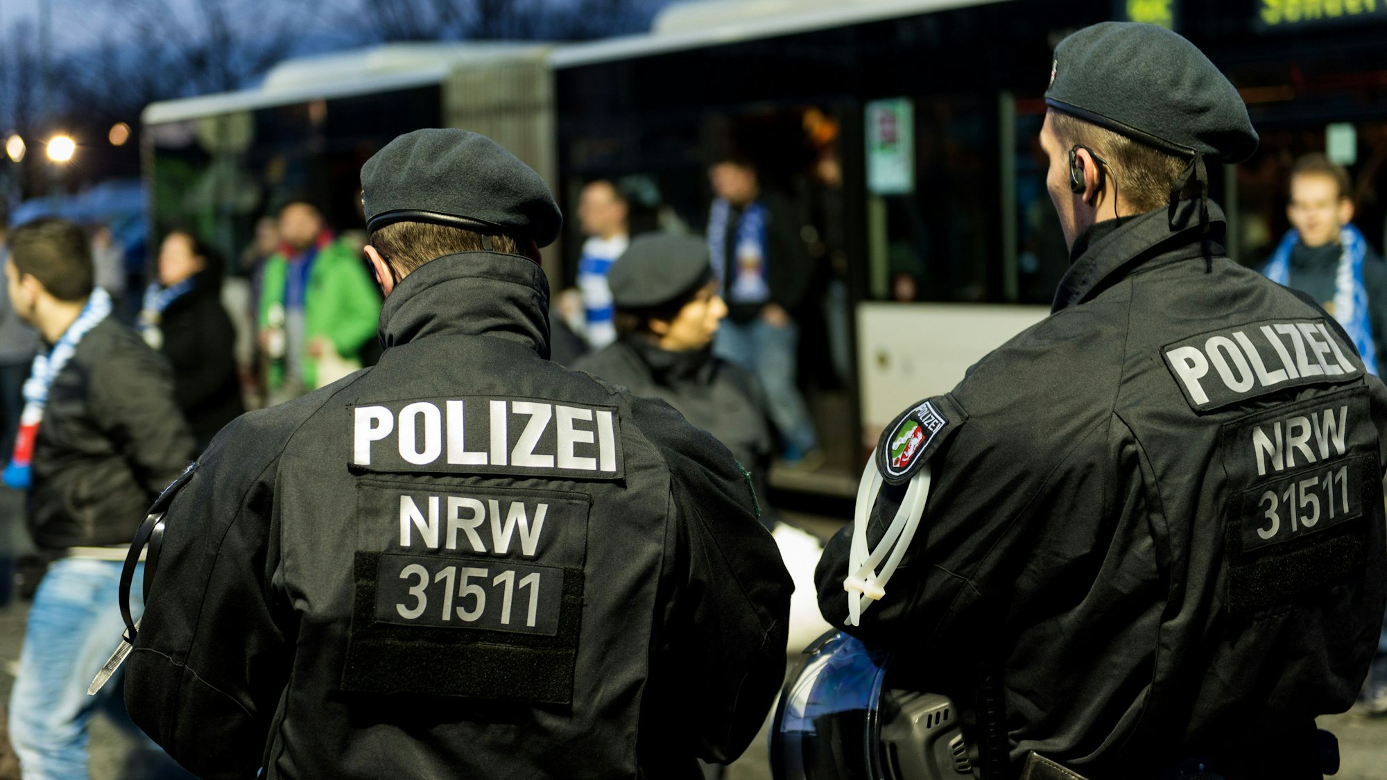ARCHIV - ILLUSTRATION - Zwei Polizisten überwachen am 20.11.2015 die Ankunft von Bussen mit Fußballfans vor dem Fußballspiel zwischen Fortuna Düsseldorf und MSV Duisburg in der ESPRIT Arena in Düsseldorf (Nordrhein-Westfalen). Die Hundertschaften der Bereitschaftspolizei in Nordrhein-Westfalen haben einen Überstundenberg angehäuft, der rund 350 Dienstjahren entspricht. In einem Bericht des NRW-Innenministeriums wird die Zahl der Überstunden bei der Bereitschaftspolizei - Stand Mitte November - mit 686 127 beziffert. Foto: Monika Skolimowska/dpa +++ dpa-Bildfunk +++