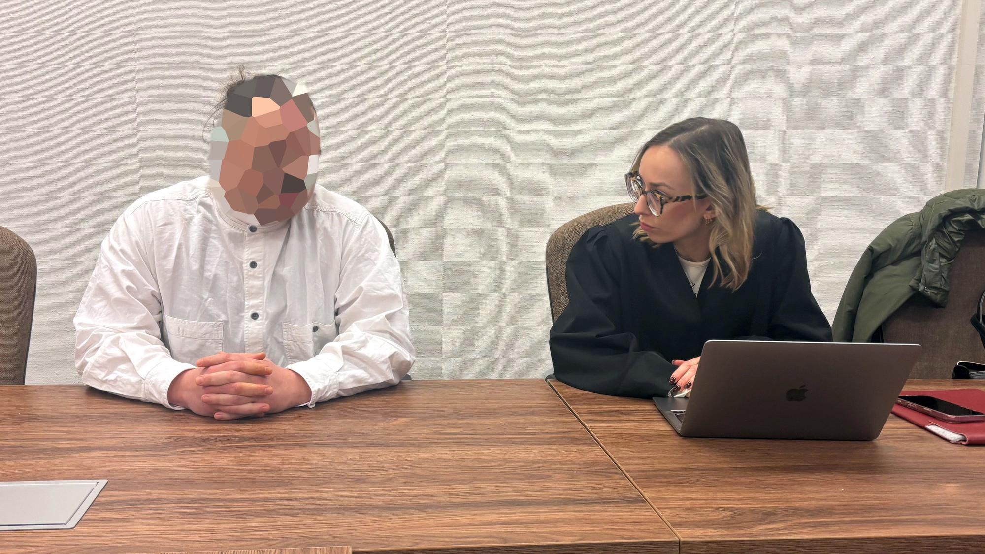 Ein Mann in einem weißen Hemd und mit verpixeltem Gesicht sitzt neben einer Frau in einer Anwaltsrobe.