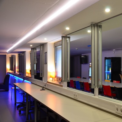 Zu sehen ist Raum mit Spiegel und Tischen.