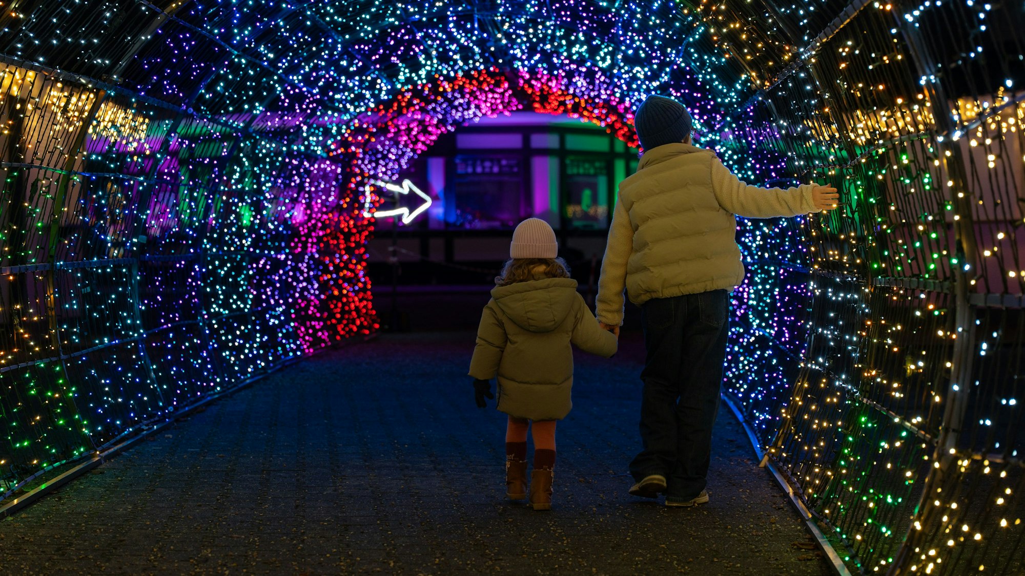 Zwei Kinder gehen durch einen Lichttunnel beim Lichtfest Garden of Lights.