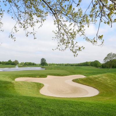 Das Bild zeigt den Golfplatz samt grüner Wiesen und Sandbunkern.