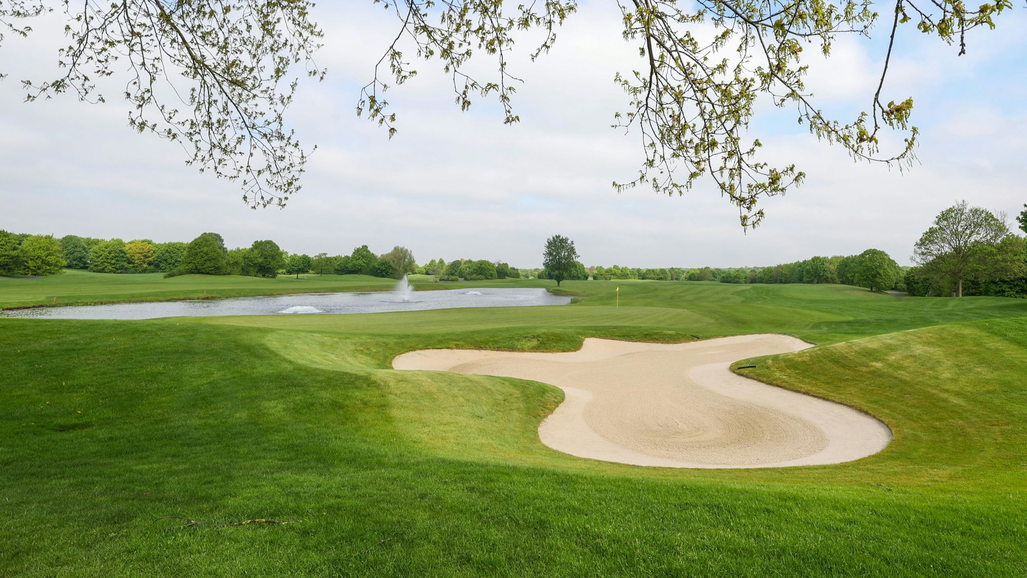 Das Bild zeigt den Golfplatz samt grüner Wiesen und Sandbunkern.