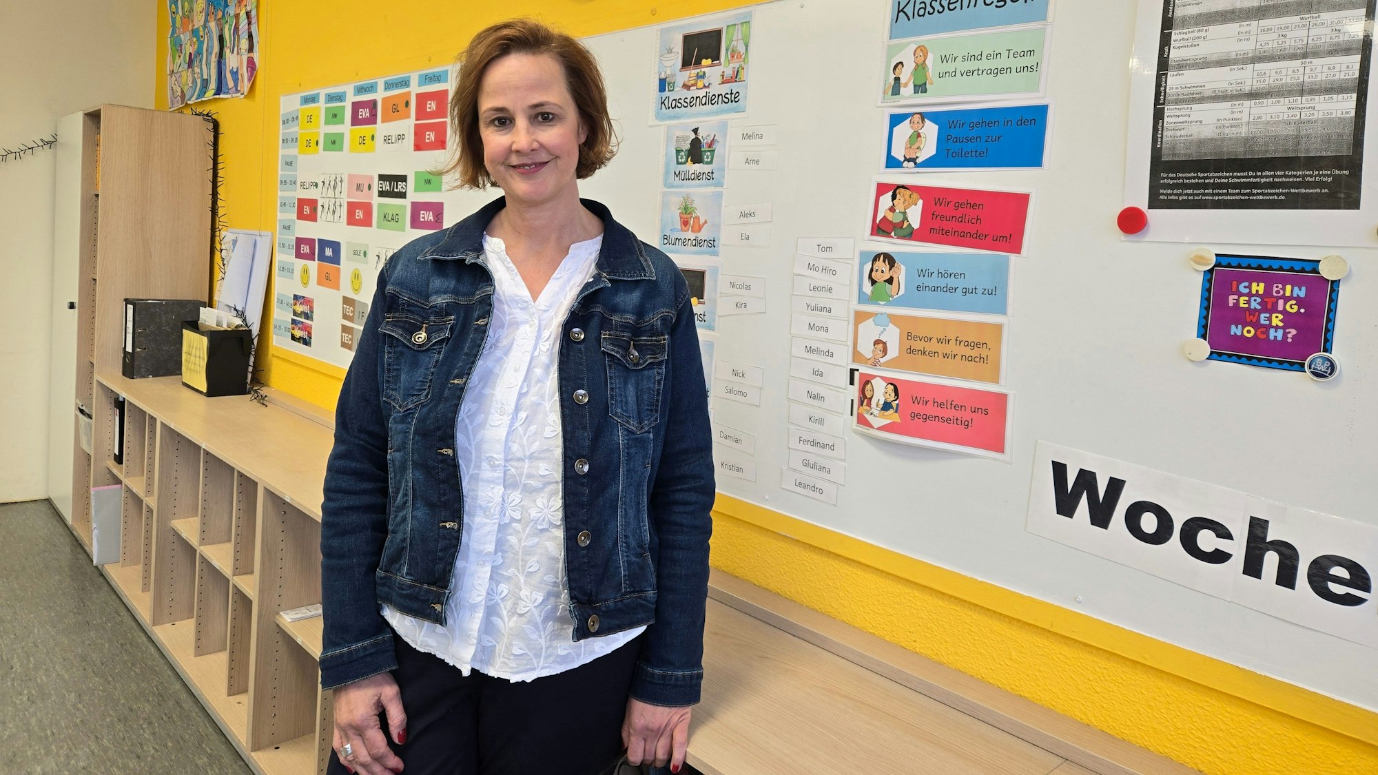 Eine Frau vor einer Pinnwand in der Schule.