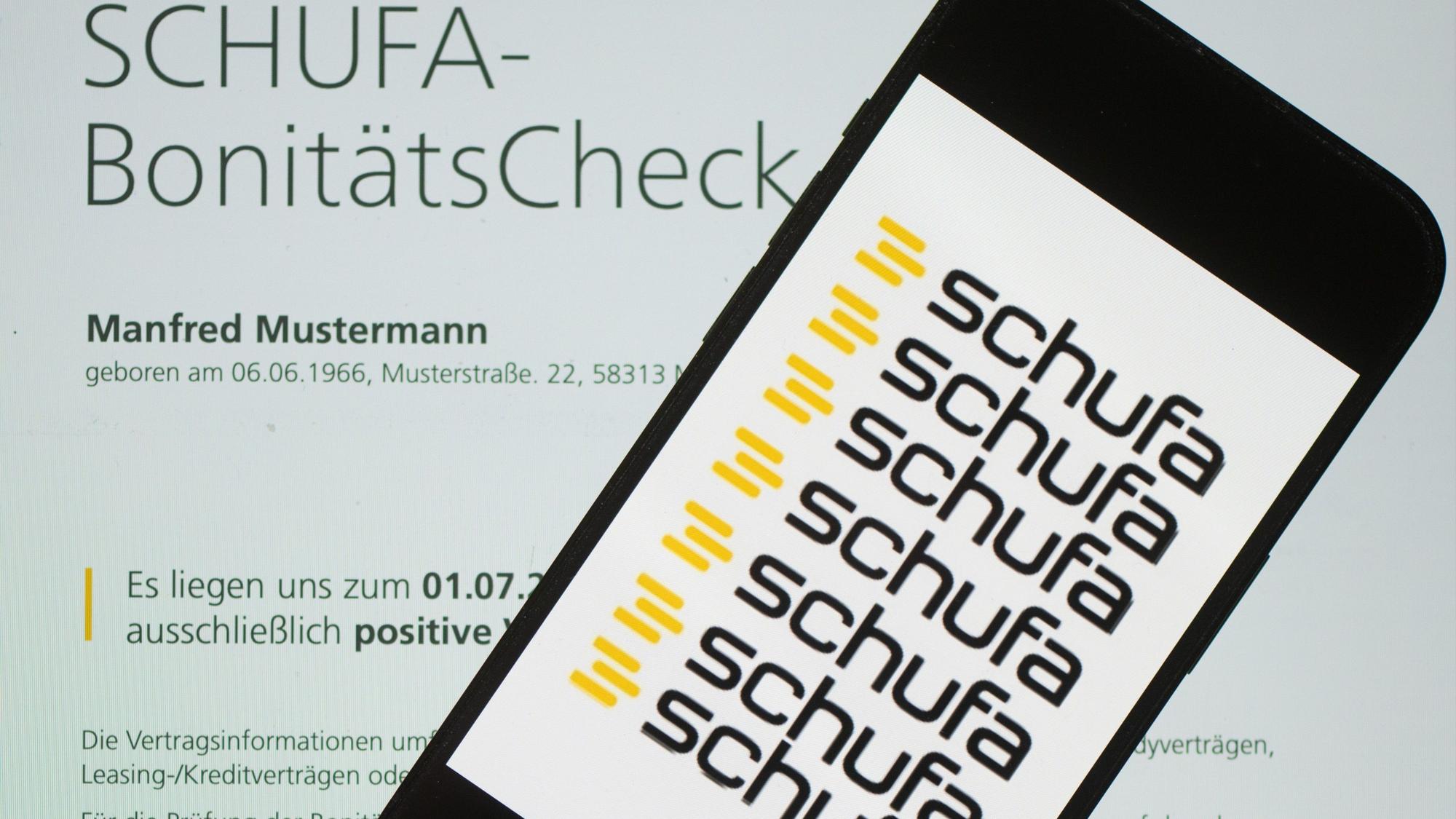 Das Logo der Wirtschaftsauskunftei Schufa liegt auf einem Display mit einem Musterdokument eines Schufa-Bonitätszertifikats. (Symbolbild)