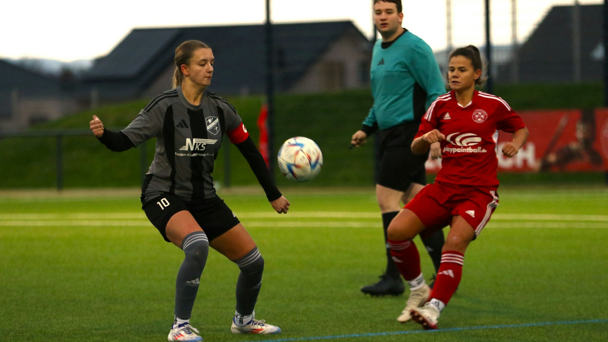 Füssenich-Geichs Spielerin Anna Bönsch kurz vor der Ballannahme. Eine Gegenspielerin und der Schiedsrichter schauen zu.