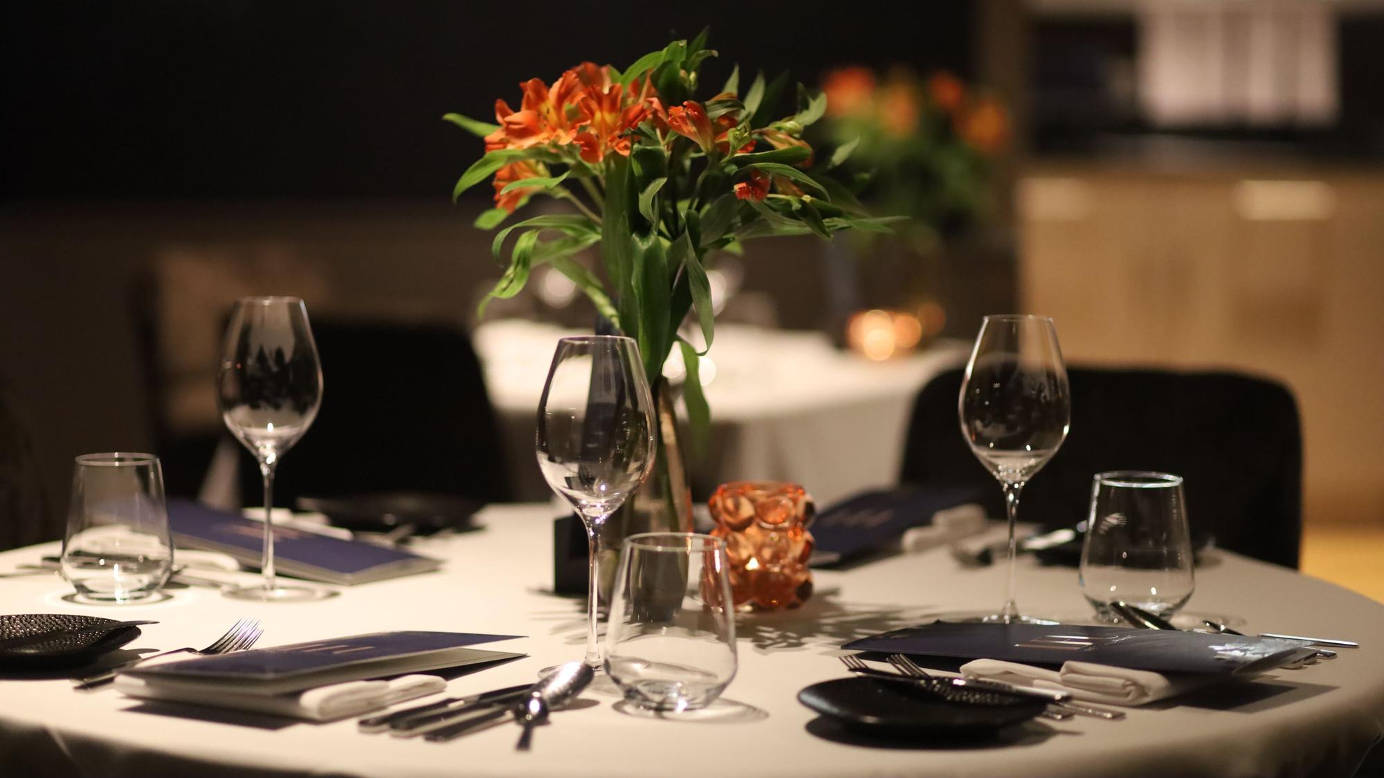 Eingedeckter Tisch mit Blumenarrangement und Weingläsern