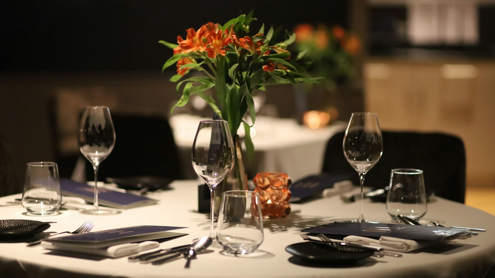 Eingedeckter Tisch mit Blumenarrangement und Weingläsern