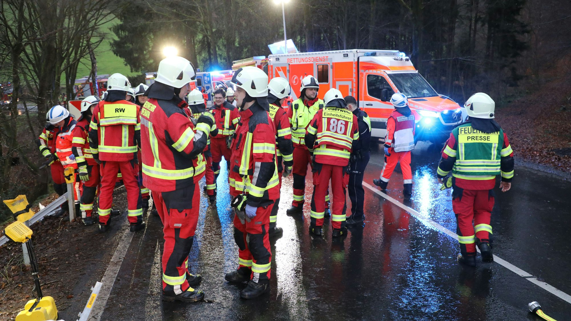 Feuerwehrleute stehen auf einer Straße.