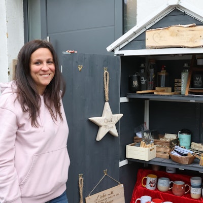 Einblick ins Sortiment: Die Künstlerin Angela Bottiglieri bietet ihre auch Ware in einem Verkaufsschrank vor ihrem Haus in der Reichshofer Ortschaft Erdingen an. Das Foto zeigt die 41-Jährige neben dem Stand vor der eigenen Haustür.