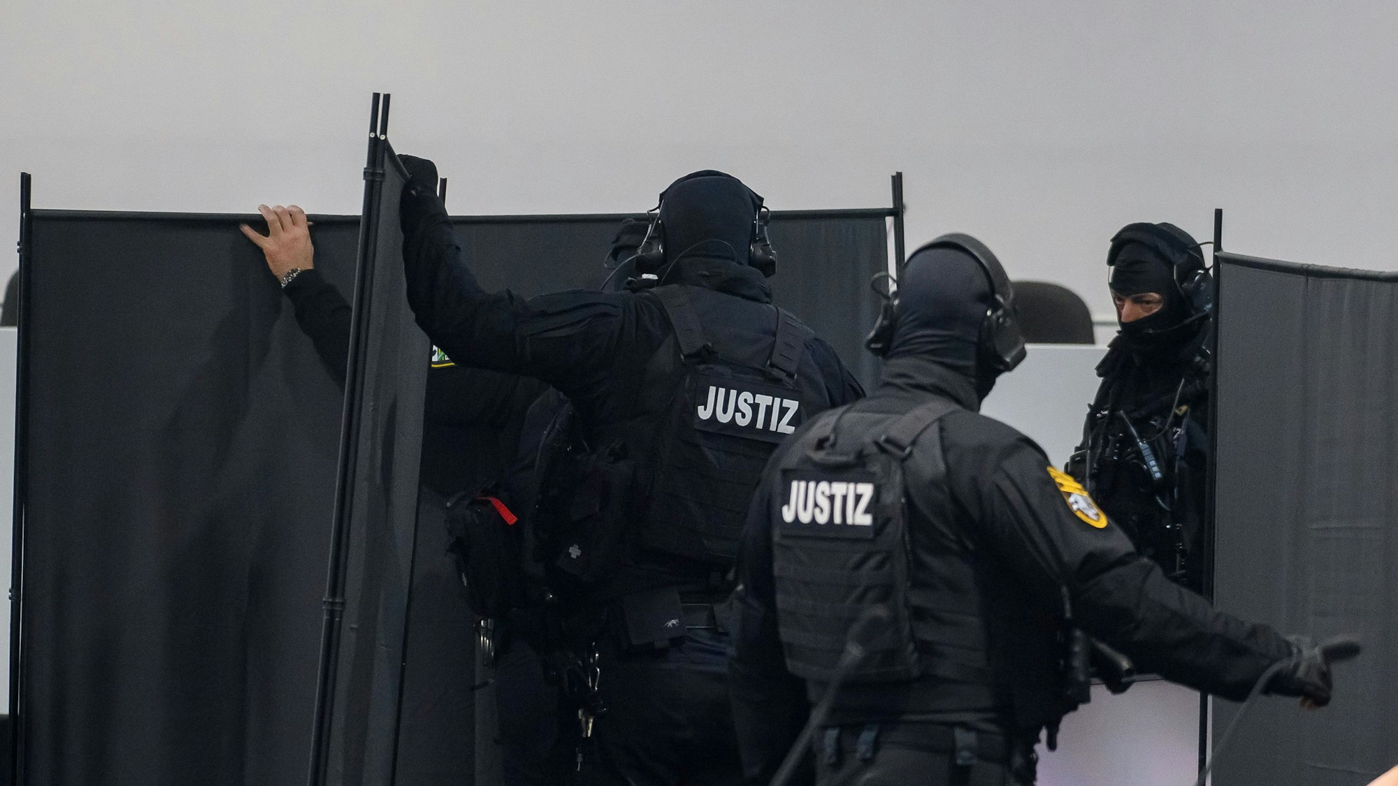 Justizbeamte stellen im Gerichtssaal des temporären Gerichtsgebäudes vom Landgericht Magdeburg probeweise Sichtschutzwände vor den Glaskasten, in dem später der Angeklagte sitzen wird.