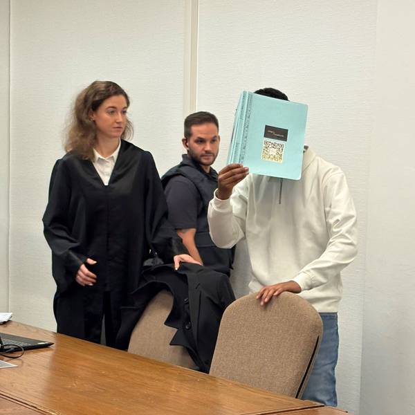 Der angeklagte 18-Jährige wird von einem Wachtmeister in den Gerichtssaal gebracht. Links seine Verteidigerin.