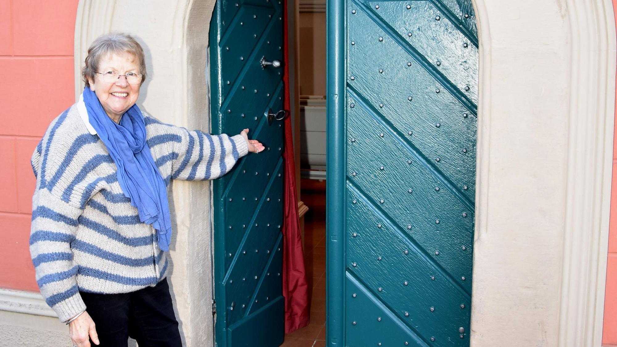 Das Foto zeigt eine Frau, die die Tür zu einer Hauskirche öffnet.