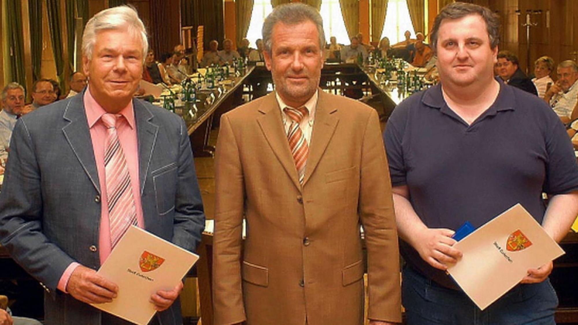 Ulf Schlüter und Guido Bachem, jeweils mit Urkunden, flankieren den Bürgermeister.
