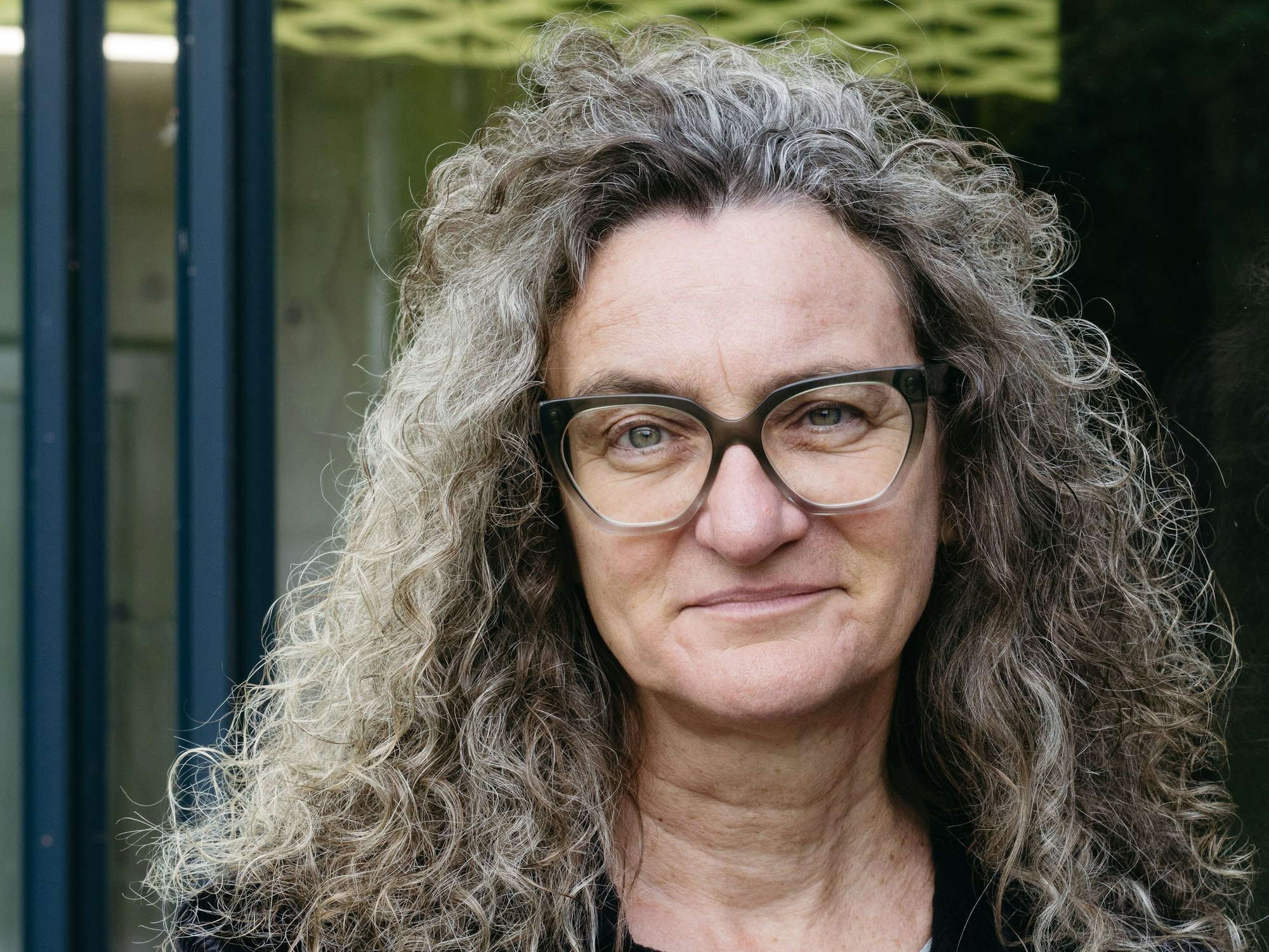 Eine Frau mit Locken schaut in die Kamera