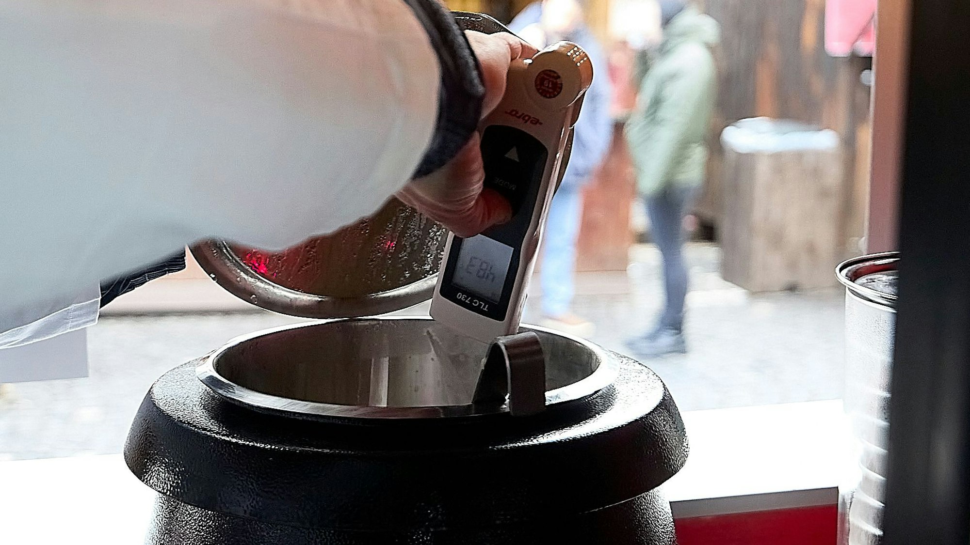 Mit einem digitalen Thermometer wird die Temperatur einer Suppe gemessen.