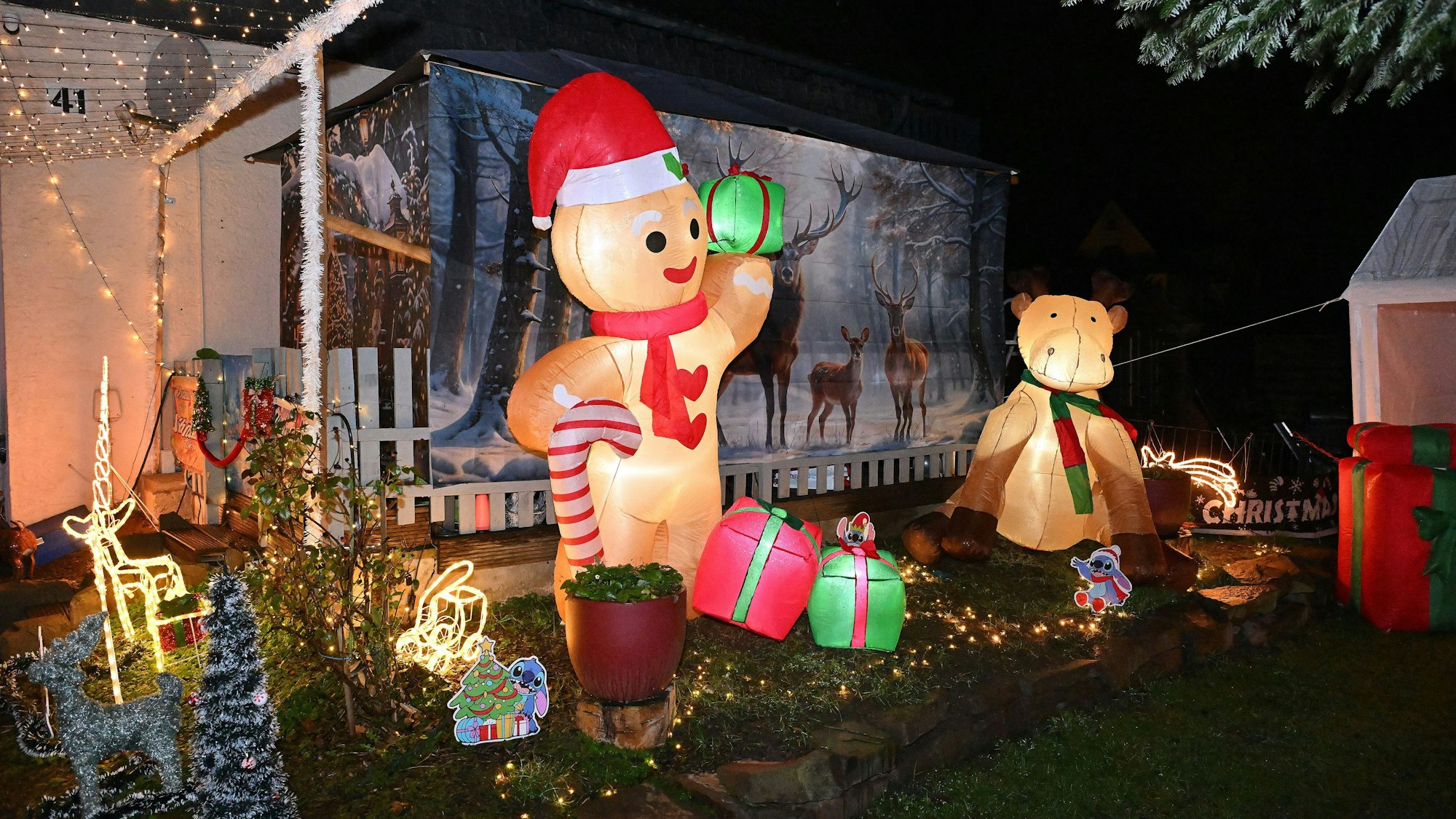 Ein aufblasbarer Lebkuchenmann im XXL-Format trägt ein Geschenk, daneben ein aufblasbares Rentier.