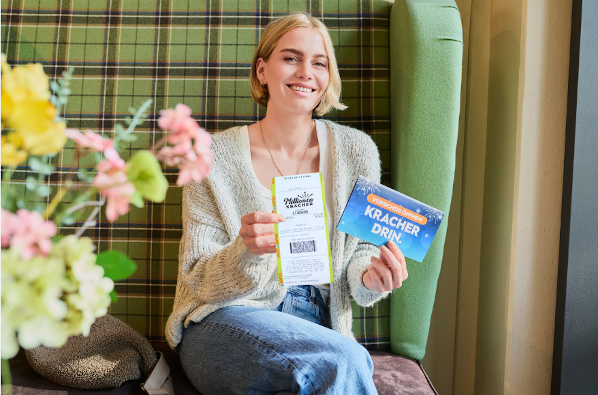 Eine Frau sitzt glücklich auf einem Sofa und hält ein MillionenKracher-Los in der Hand.
