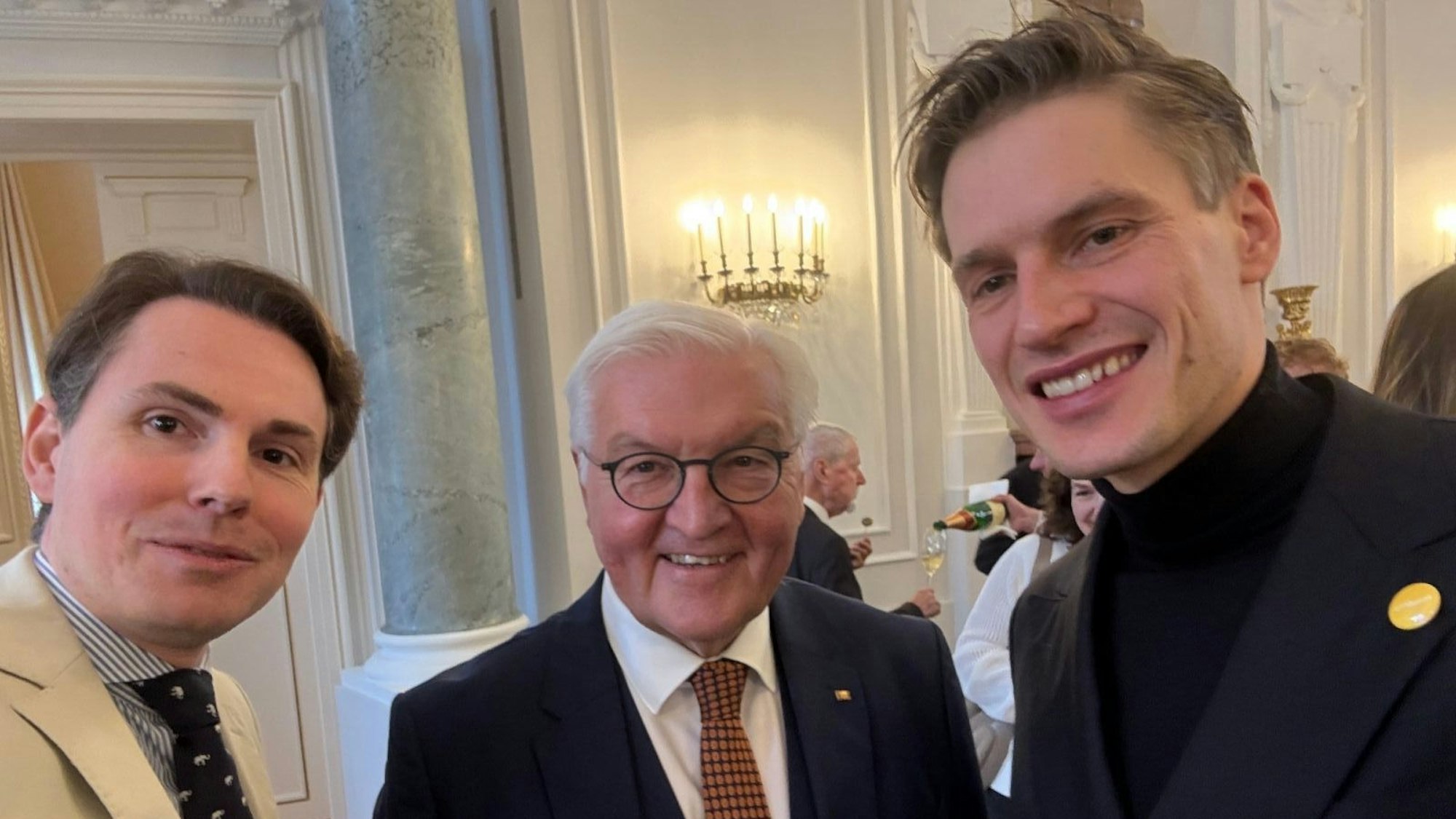 Die drei Männer lächeln in die Kamera.