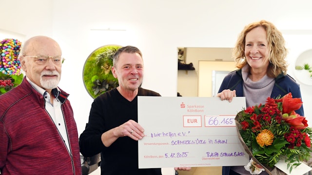 Goldschmiedemeister Herbert Schmelzer und Friseurmeister Ralph Schwalbach überreichen Isabella Neven DuMont für „wir helfen“ einen symbolischen Scheck.