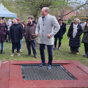 Zu sehen ist ein Mann auf einem Trampolin, um ihn herum stehen mehrere Menschen.
