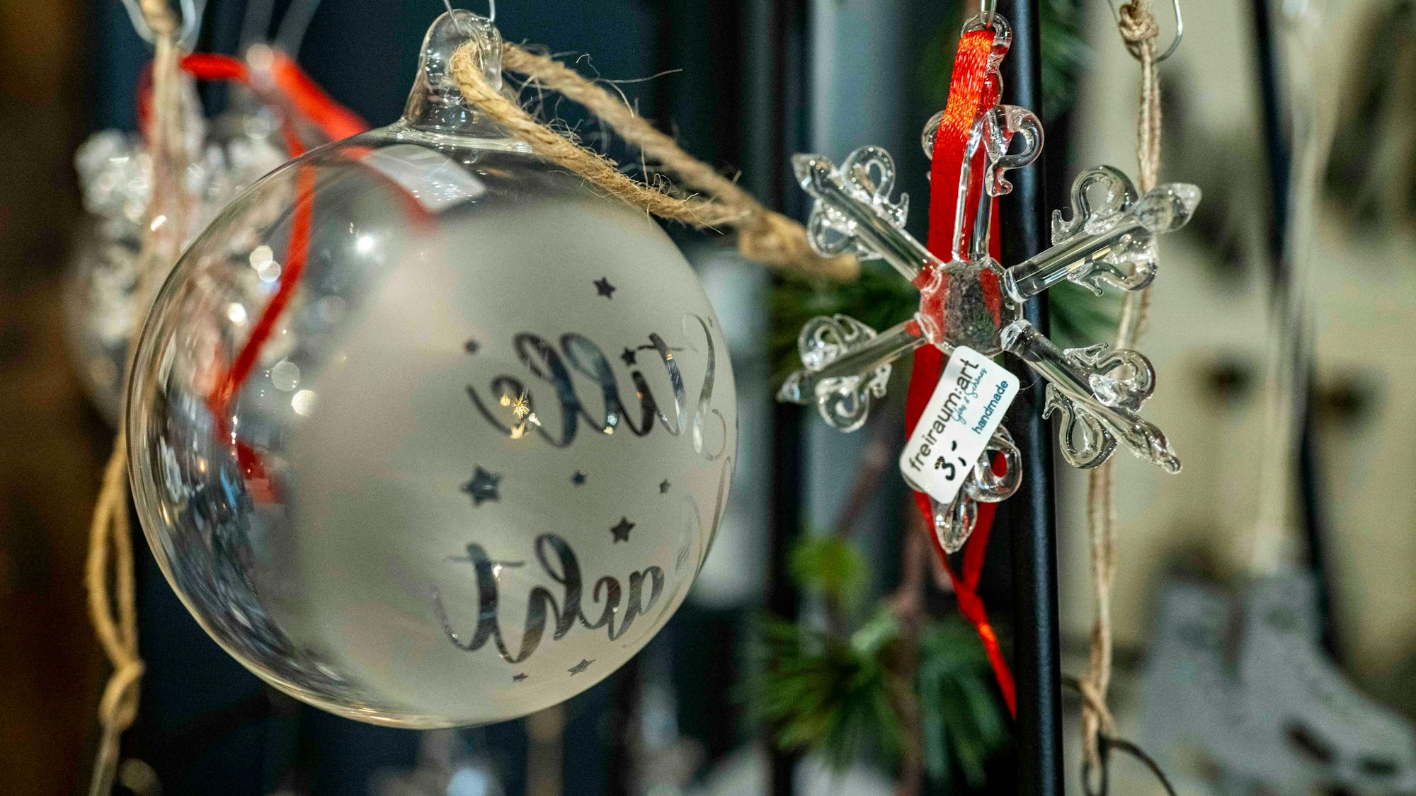 Das Bild zeigt eine gläsene Weihnachtskugel und einen Weihnachtsstern aus Glas.