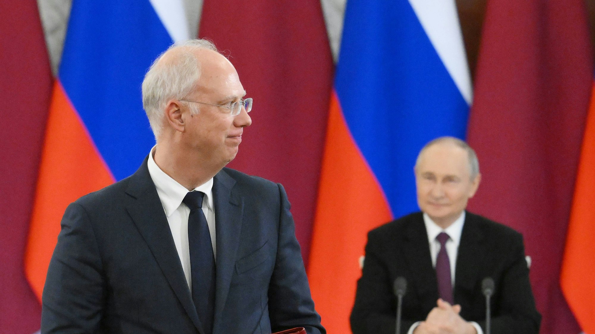 Kirill Dmitrijew und Kremlchef Wladimir Putin (im Hintergrund). Der russische Chefunterhändler hat Kanzler Merz bei X verspottet. (Archivbild)