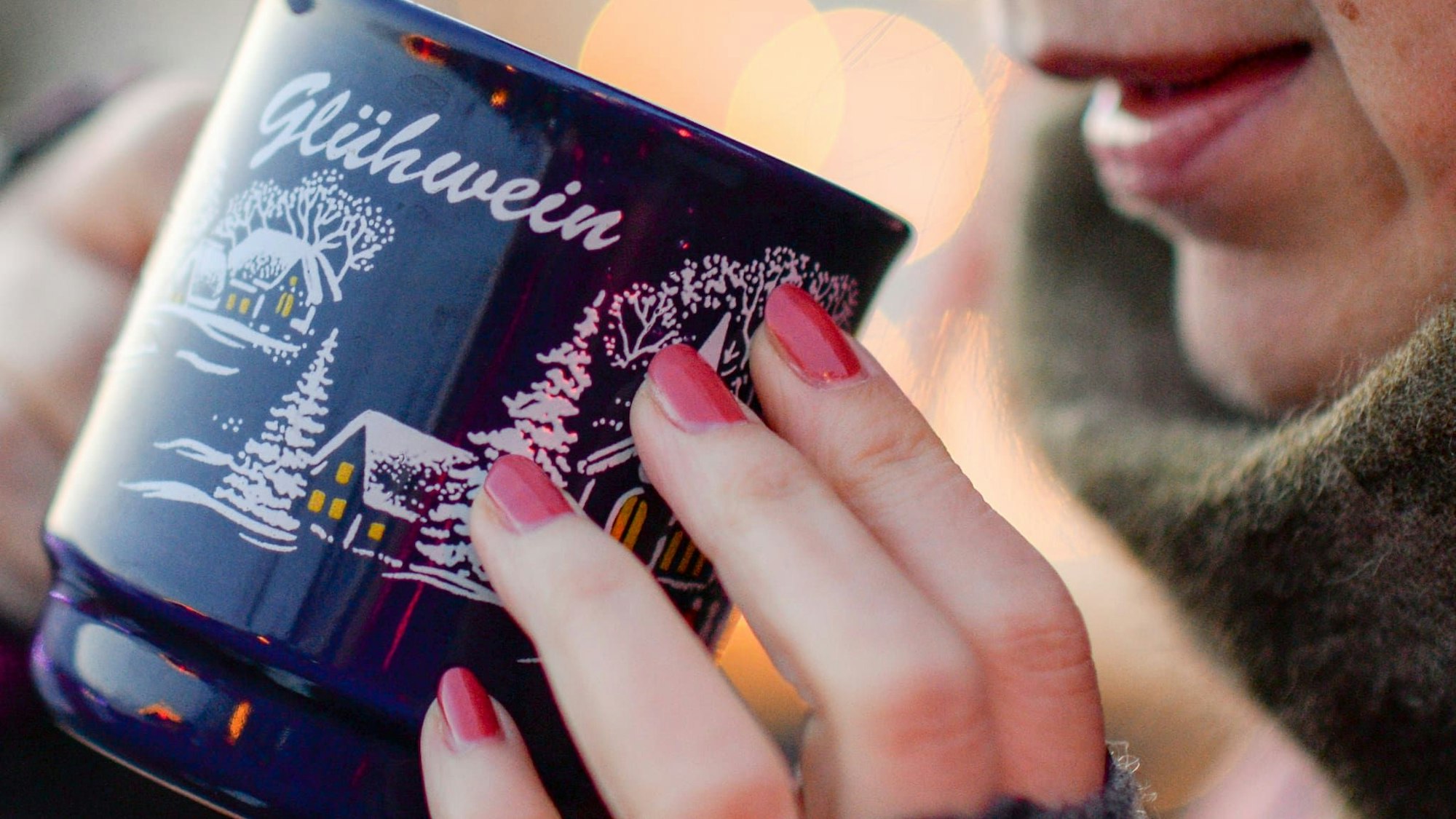 Eine Frau hält eine Tasse mit Glühwein in den Händen.