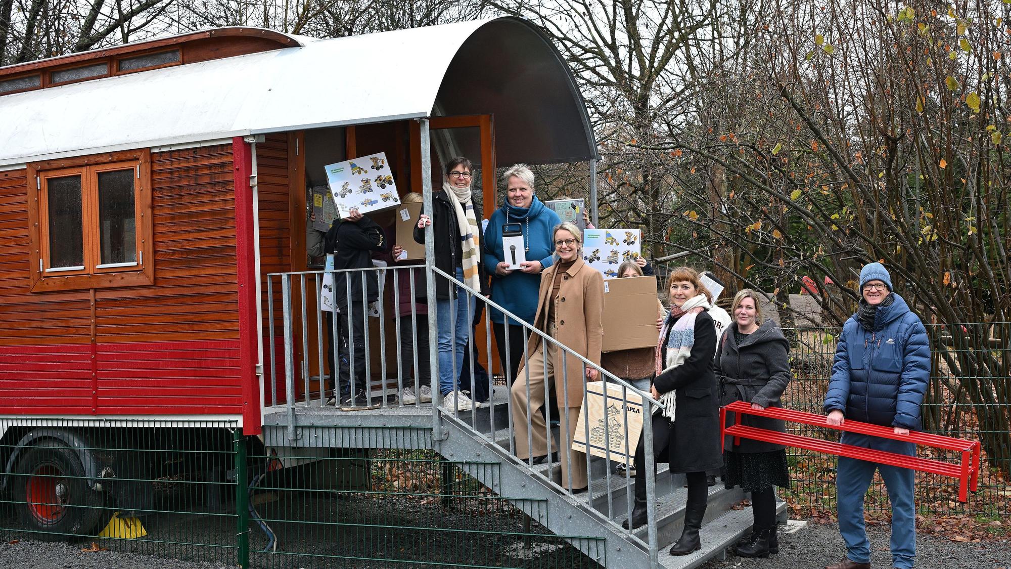 Ein umgebauter Zirkuswagen mit Treppe, darauf stehen viele Menschen.