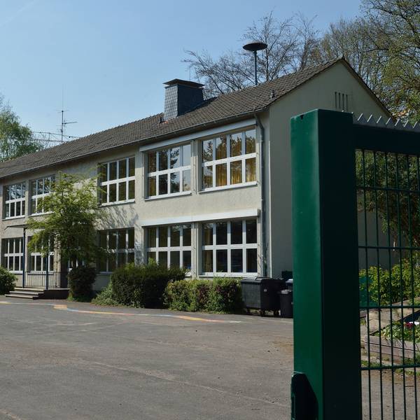 Das Schultor steht offen. Der Blick fällt auf das Hauptgebäude.