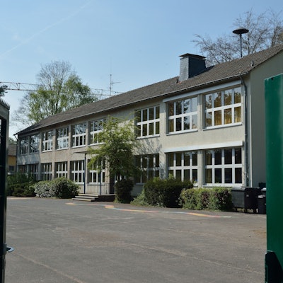 Das Schultor steht offen. Der Blick fällt auf das Hauptgebäude.