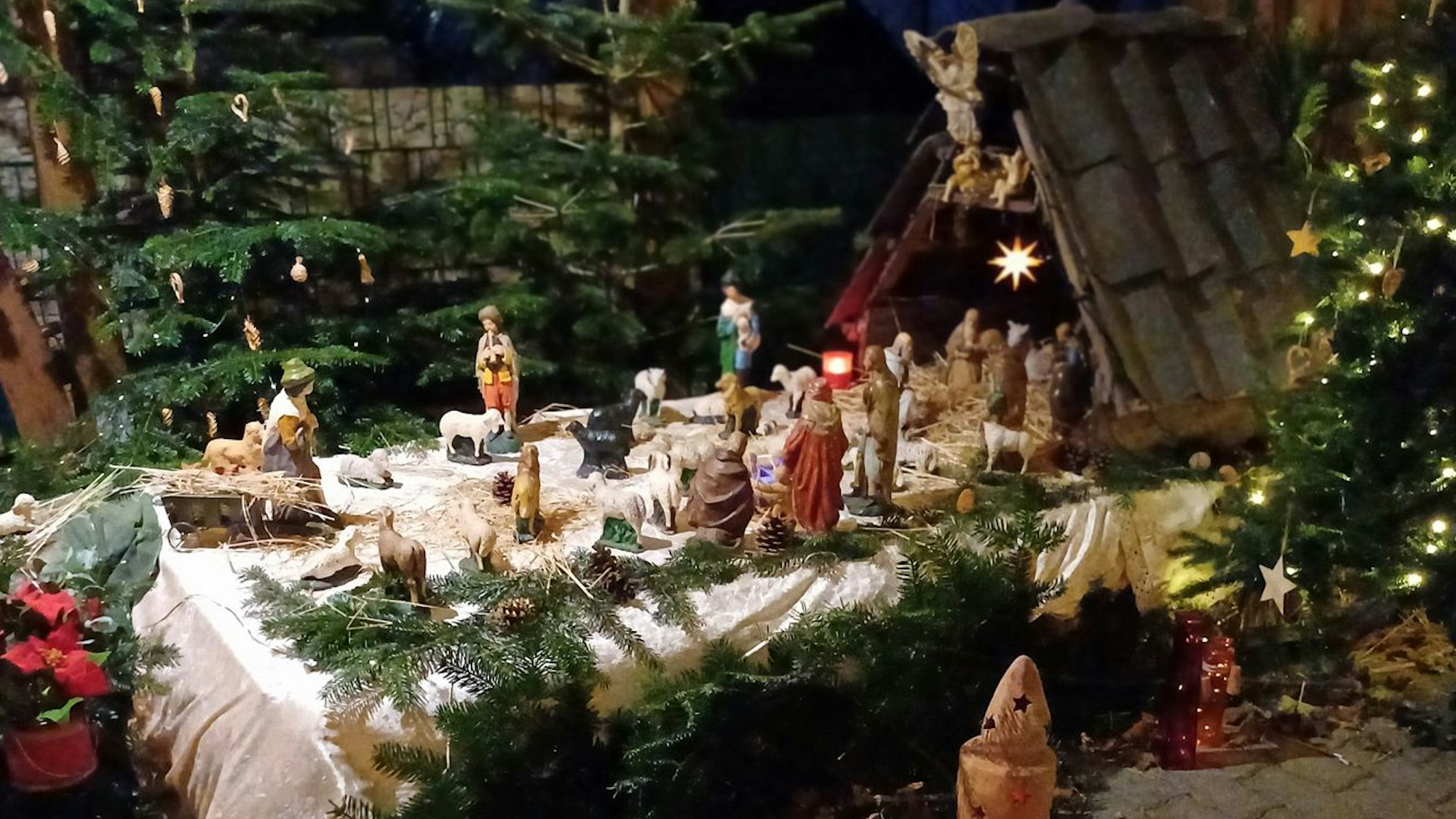 Geschnitzte Krippenfiguren, Tannengrün und Lichterketten.