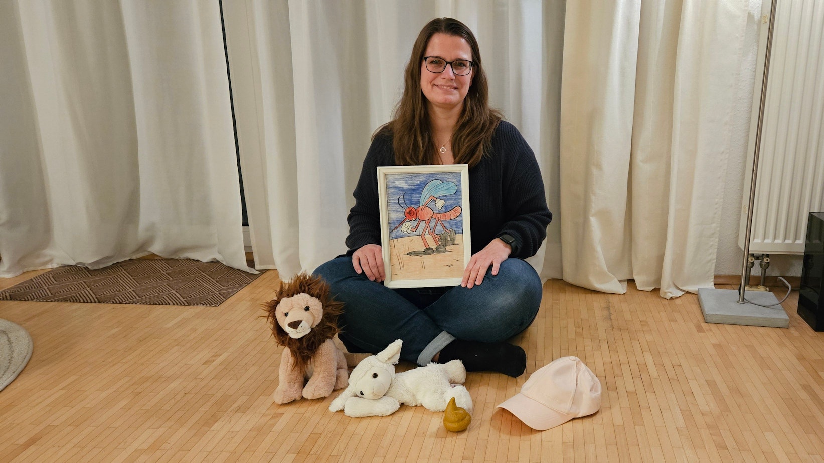 Auf dem Bild ist eine auf dem Boden sitzende Frau mit Stofftieren zu sehen.