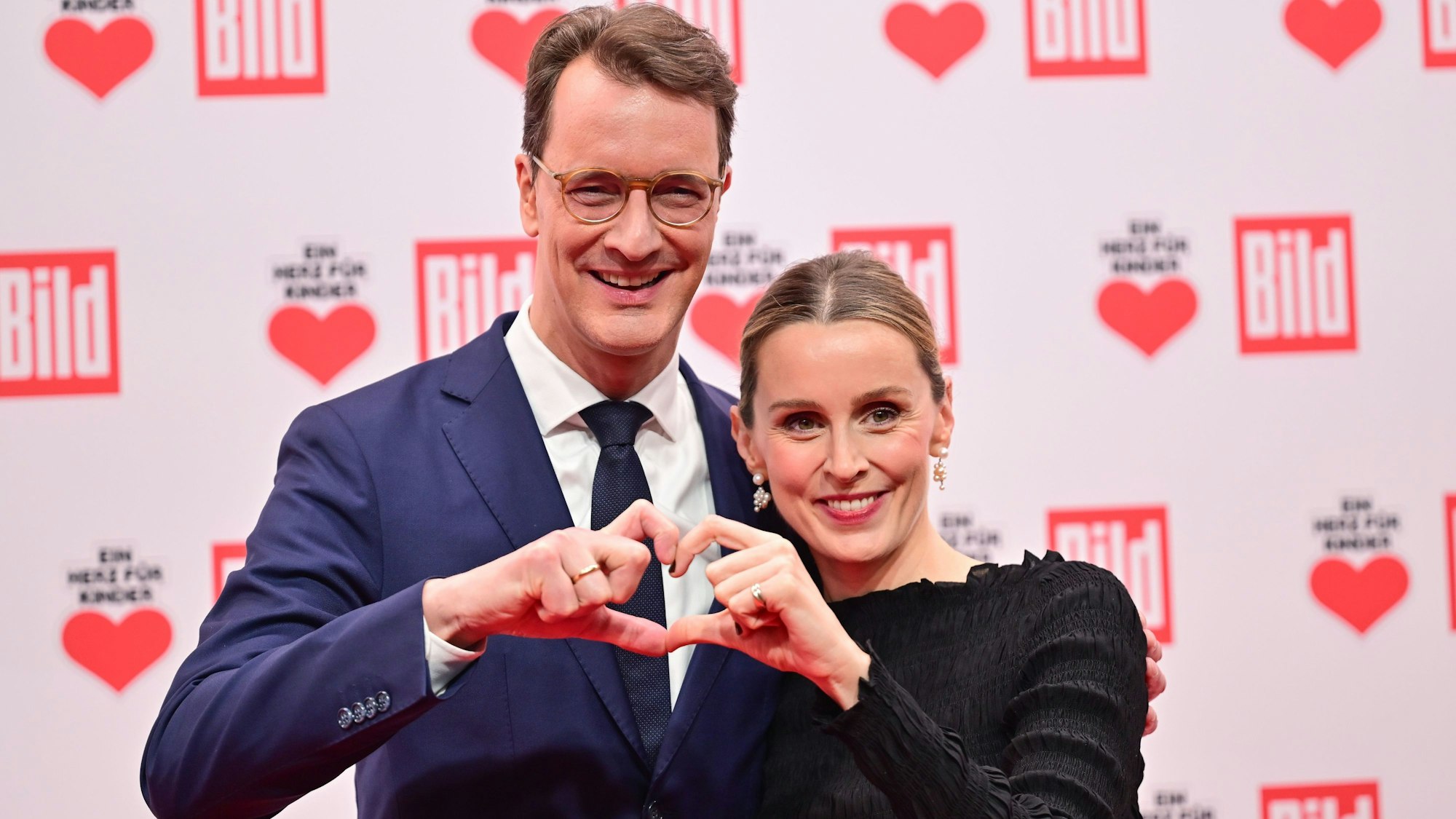 Hendrik Wüst (CDU), Ministerpräsident von Nordrhein-Westfalen, und seine schwangere Frau Katharina stehen vor Beginn der Spenden-Gala „Ein Herz für Kinder“ auf dem Roten Teppich.