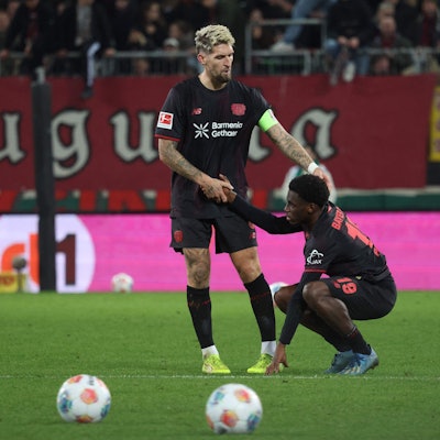 Bayer Leverkusen's German midfielder #08 Robert Andrich (L) helps up deceived Bayer Leverkusen's Dutch forward #19 Ernest Poku after the end of the German first division Bundesliga football match between FC Augsburg and Bayer Leverkusen in Augsburg, southern Germany, on December 6, 2025. (Photo by Karl-Josef HILDENBRAND / AFP) / DFL REGULATIONS PROHIBIT ANY USE OF PHOTOGRAPHS AS IMAGE SEQUENCES AND/OR QUASI-VIDEO
