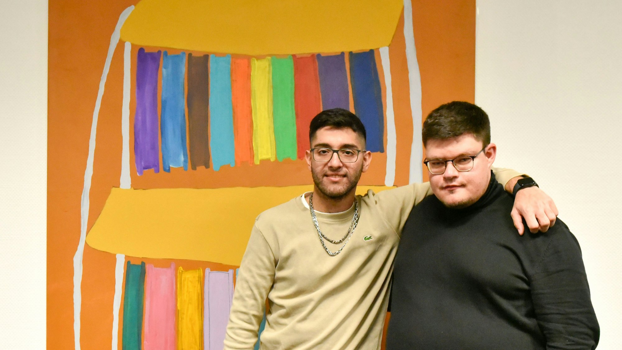 Auf dem Bild sind zwei junge Künstler vor einem Bild zu sehen.