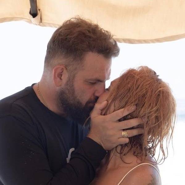 Roman Novak und seine Frau küssen sich auf einem Urlaubstrip.