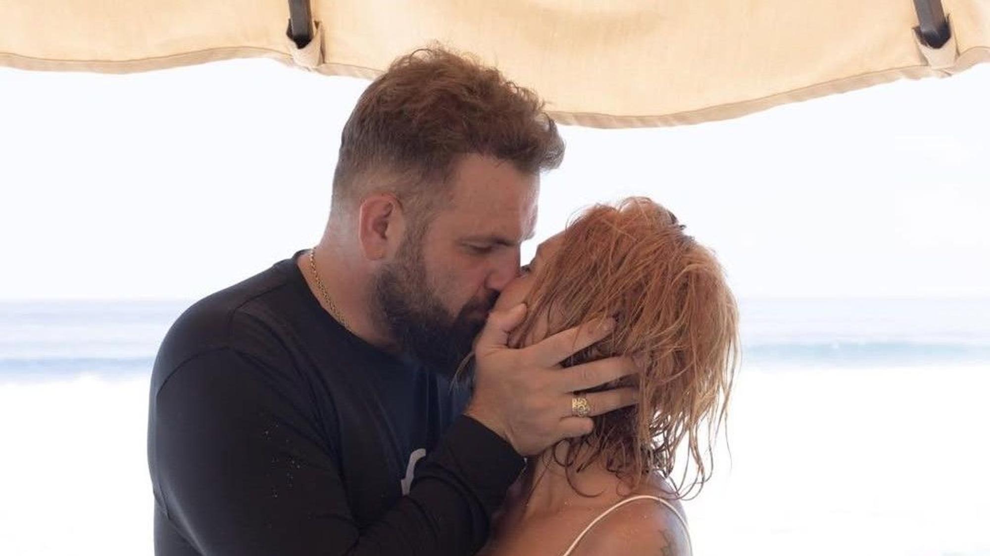 Roman Novak und seine Frau küssen sich auf einem Urlaubstrip.