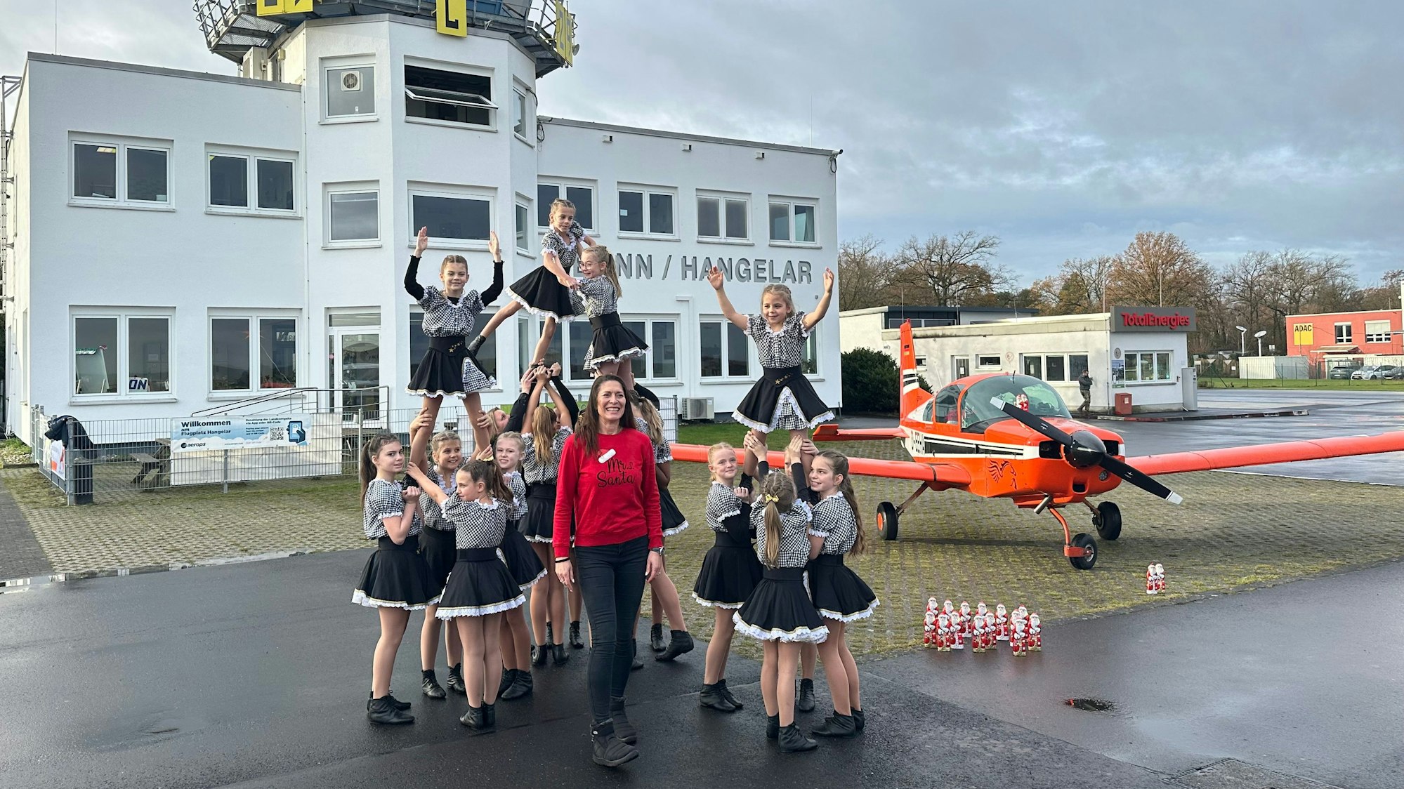 Eine Tanzfigur vor dem Tower des Flugplatzes präsentieren die Karnevalistinnen der „Stääneflejer“, in der Mitte Organisatorin Kathrin Kaiser.