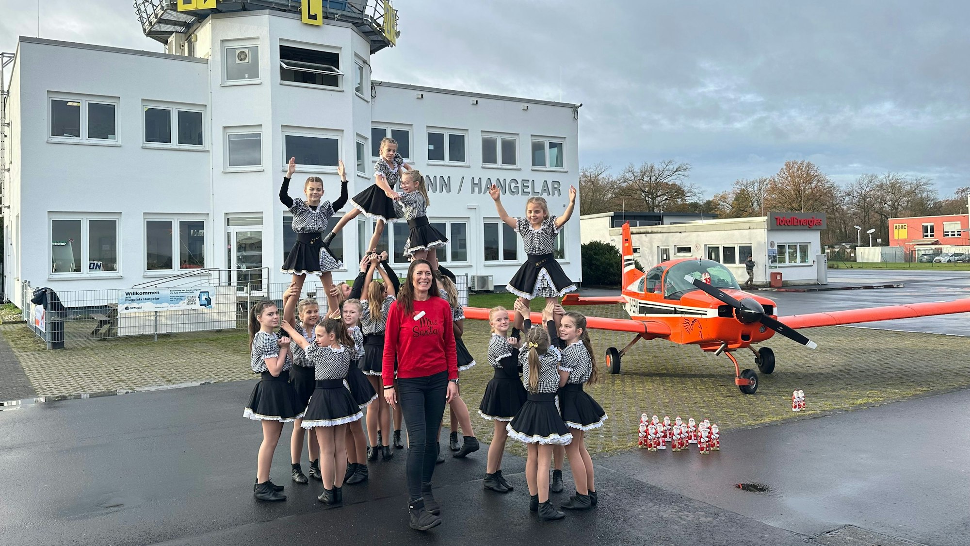 Eine Tanzfigur vor dem Tower des Flugplatzes präsentieren die Karnevalistinnen der „Stääneflejer“, in der Mitte Organisatorin Kathrin Kaiser.