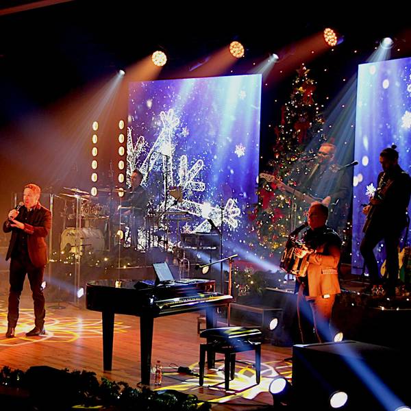 Die Band steht auf der Bühne, die mit weihnachtlichen Motiven beleuchtet ist.