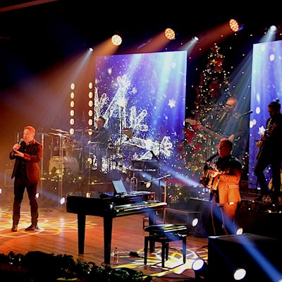 Die Band steht auf der Bühne, die mit weihnachtlichen Motiven beleuchtet ist.