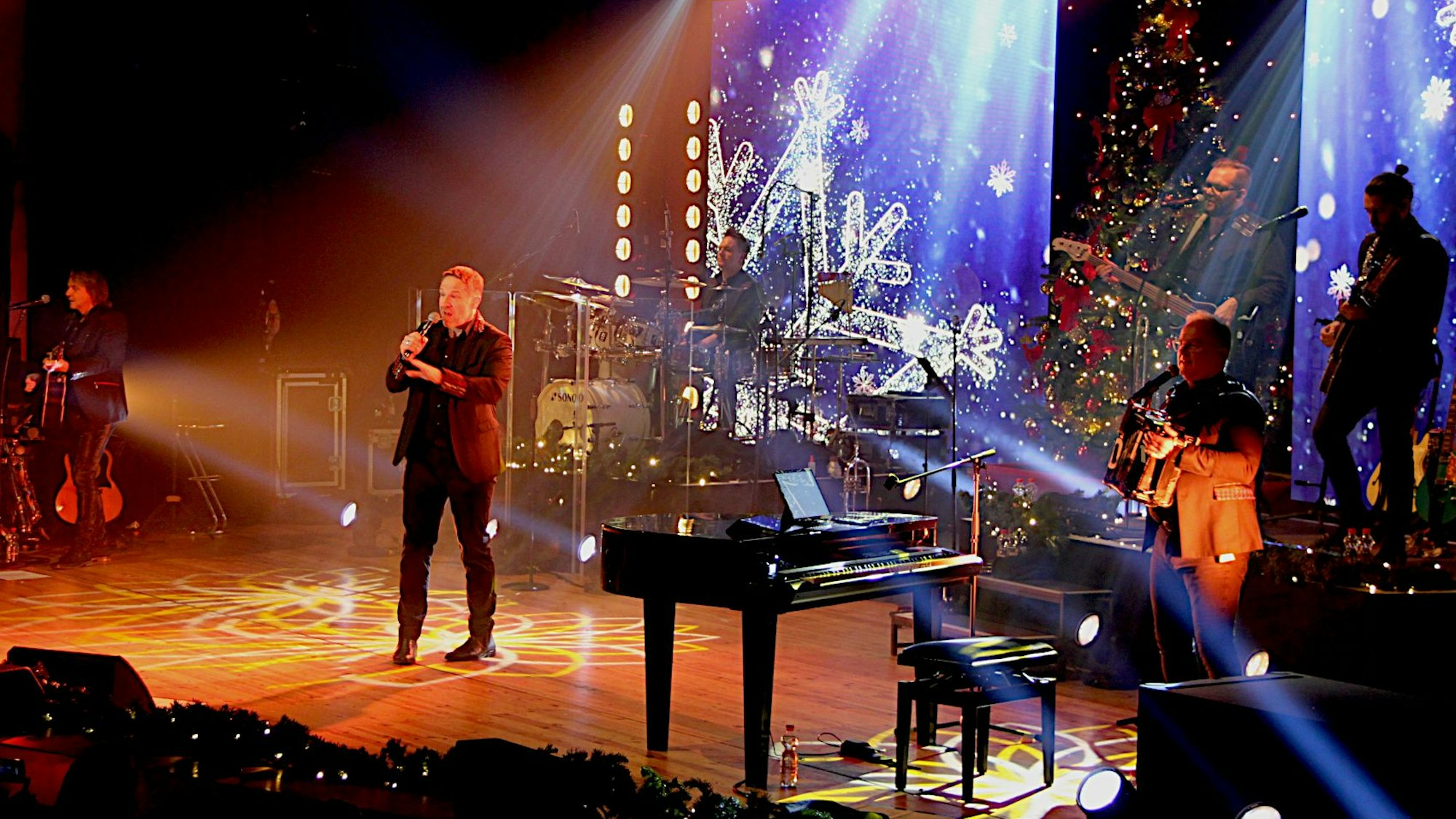 Die Band steht auf der Bühne, die mit weihnachtlichen Motiven beleuchtet ist.